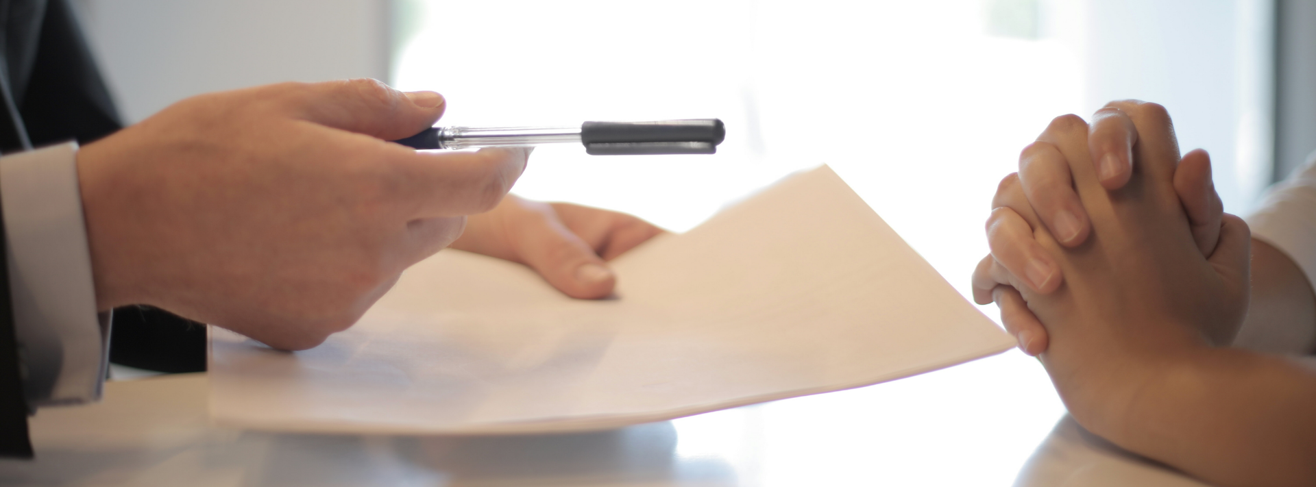 une personne tend un stylo vers une autre